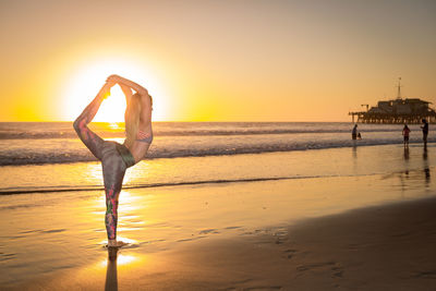 Woman standing on beach against clear sky during sunset