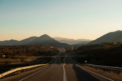 Asphalt road among mountains at sunset