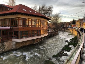 Bridge over river by buildings in city against sky