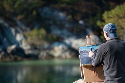 Man painting against lake