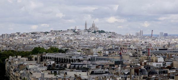 View of cityscape against cloudy sky