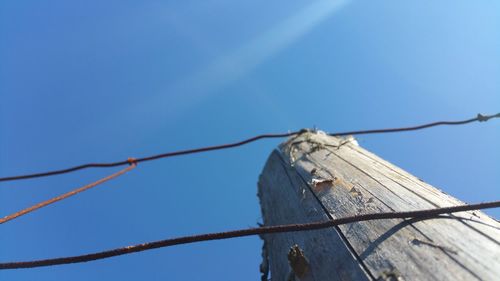 Low angle view of barbed wire against clear blue sky