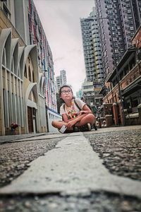 Portrait of young woman sitting on buildings in city