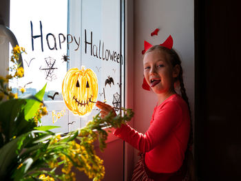 Child painting pumpkin window preparing celebrate halloween kid draws decorates room with paper bats