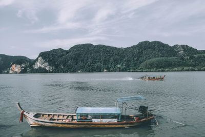 Boats moored on sea against mountains