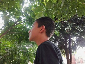 Rear view of boy standing against trees