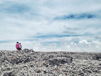 Silhouette of people on landscape against cloudy sky