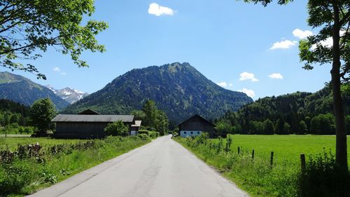 Street amidst grassy field against mountains and sky