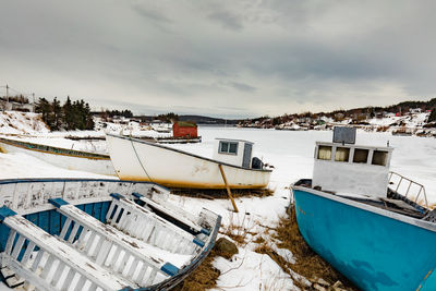 Boats moored in snow against sky