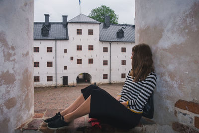 Side view of woman sitting outside building