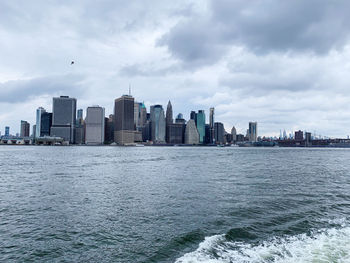 Sea by buildings against sky in city