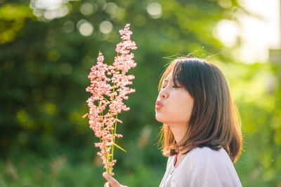 Woman blowing flower during sunny day