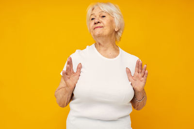 Portrait of young woman standing against yellow wall