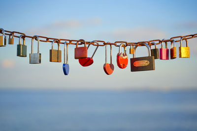 Close-up of padlocks hanging on metal against sky