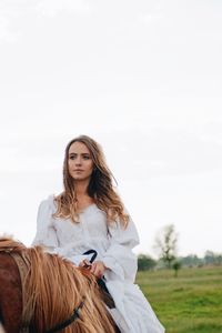 Young woman riding horse on field