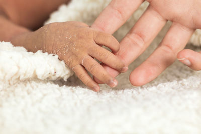 Crop unrecognizable woman hand holding tiny newborn baby hand