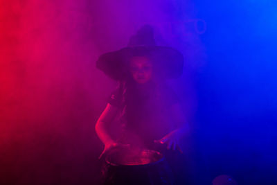 Woman standing against illuminated light painting