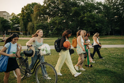 Smiling teenage girls walking together at park during sunset