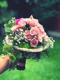 Close-up of hand holding rose bouquet in park