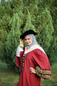 Young woman wearing hat standing against trees