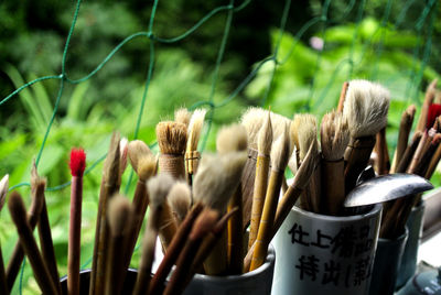 Close-up of paintbrushes in containers by netting