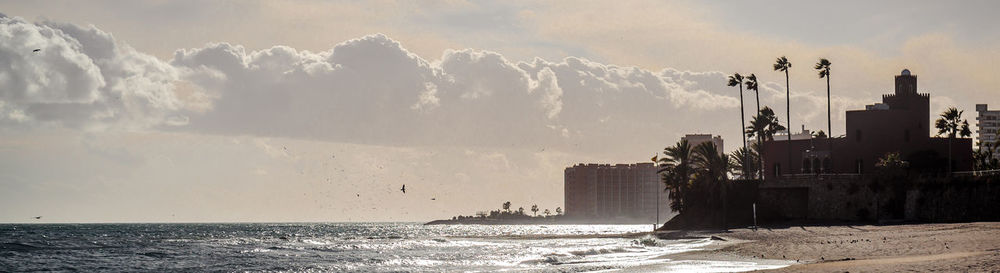 Panoramic shot of sea and buildings against sky