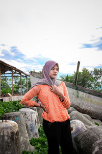 Young woman standing on rock against sky