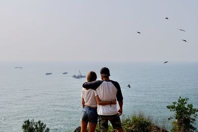 Rear view of couple looking at sea against sky