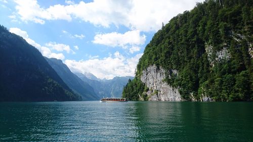 Scenic view of river and rocky mountains against sky