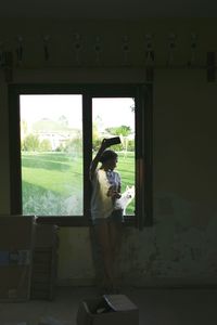 Full length of woman looking through window