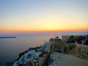 Town in santorini by aegean sea against sky during sunset