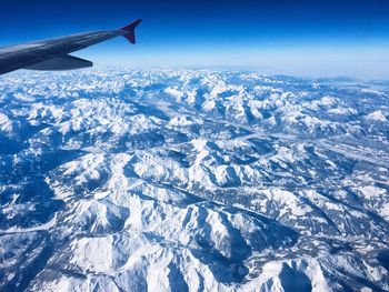 Aerial view of snowcapped landscape against blue sky