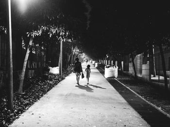 Full length of woman walking on footpath at night