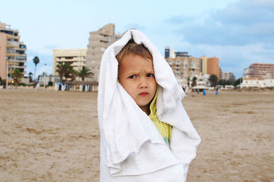 Portrait of baby wrapped in towel standing at beach