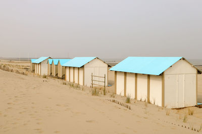 Huts on beach by sea against clear sky