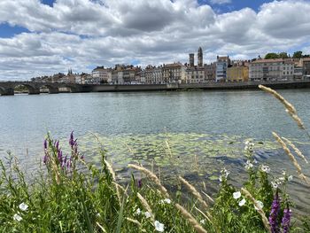 Scenic view of river by cityscape against sky