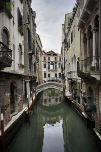 Canal amidst buildings in city against sky