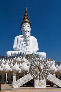 Low angle view of sculpture against building against clear blue sky