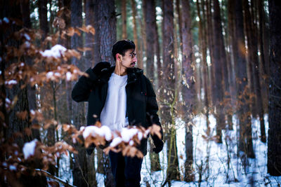Young man standing in forest during winter