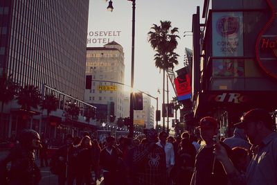 People on city street by buildings against sky