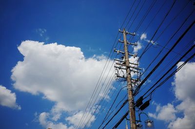 Low angle view of electricity pylon against blue sky