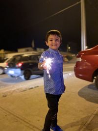Portrait of boy standing by car at night