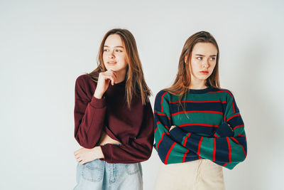 Young twins standing against white background