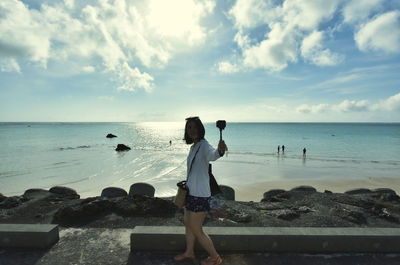 Woman standing at beach against sky