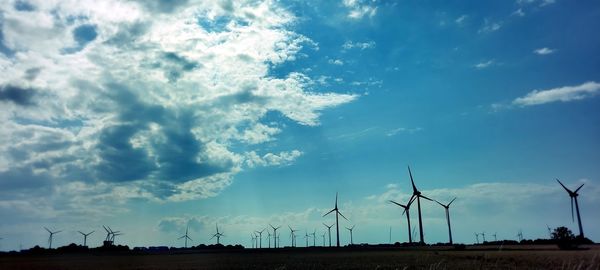Low angle view of windmills on landscape against sky