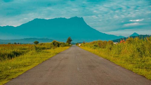 Road leading towards mountains against sky