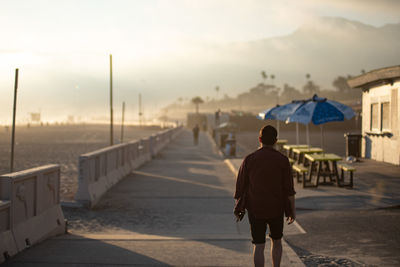 Rear view of man walking on footpath against sky