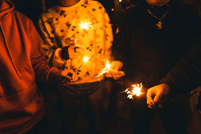 Midsection of people holding sparklers