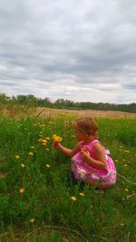 Side view of girl playing on field against cloudy sky