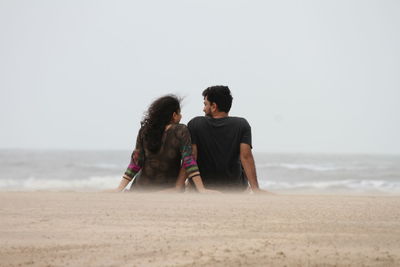 Young couple on beach against sky